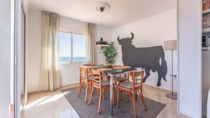 Ein Essbereich mit Tisch, Stühlen, einer Pendelleuchte, einem Blumentopf und einer StierSilhouette an der Wand.