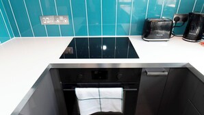 A kitchen with a black stove, oven, and a white countertop. - Modern 2-Bed Apartment Near Kingston - Pass the Keys (Kingston-upon-Thames)