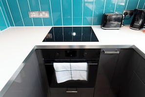 A kitchen with a black stove, oven, and a white countertop. - Modern 2-Bed Apartment Near Kingston - Pass the Keys (Kingston-upon-Thames)