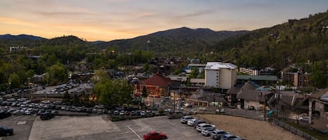 A parking lot with cars, buildings, and a mountainous backdrop.