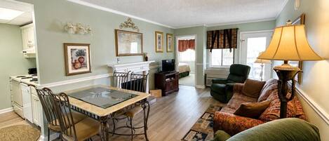 A living room with a dining table, chairs, a sofa, and a lamp.