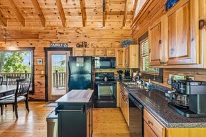 A wooden cabin interior with a kitchen, dining area, and a sign that reads 'FAMILY.' - 4BR w/Mountain Views! Hot Tub*Game Room*Sauna (Sevierville)