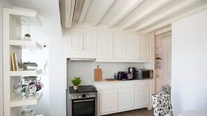 Uma cozinha compacta com armários brancos, fogão, micro-ondas e uma pequena área de refeições.