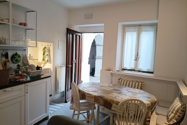 Una cocina compacta con comedor, una ventana con cortinas y vista a un edificio.