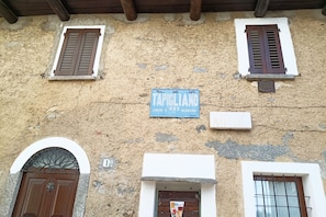 Une façade d’immeuble avec une enseigne indiquant « TAPIGLIANO », une arche en pierre et une porte en bois.