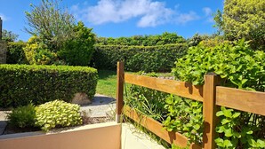 Un jardín con cerda de madera, setos bien recortados y diversas plantas.