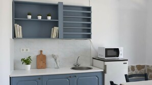 A kitchen with a white countertop, a sink, a microwave, and a blue cabinet with shelves above. - Santorini Stay With Hot Tub (Patmos)