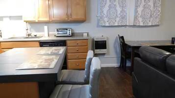 Una cocina compacta con armarios de madera, lavavajillas, tostadora y refrigerador pequeño.