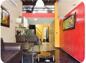 A hotel lobby with a seating area, a staircase, and a kitchen in the background. - 66 Beautiful apartment in poblado near Éxito and metro station (Medellín)