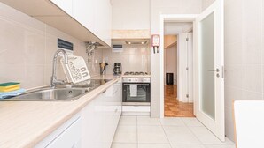 Eine Küche mit Spüle aus Edelstahl, einem Herd und einem Kühlschrank.