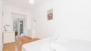 Una camera d'albergo con un letto, una scrivania, una sedia, una finestra e un ingresso a un balcone.