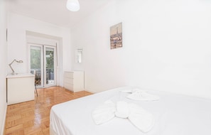 Ein Hotelzimmer mit Bett, Schreibtisch, Stuhl, Fenster und einer Tür, die auf einen Balkon führt.