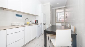 Una cucina moderna con mobili bianchi, un tavolo da pranzo nero e una finestra.