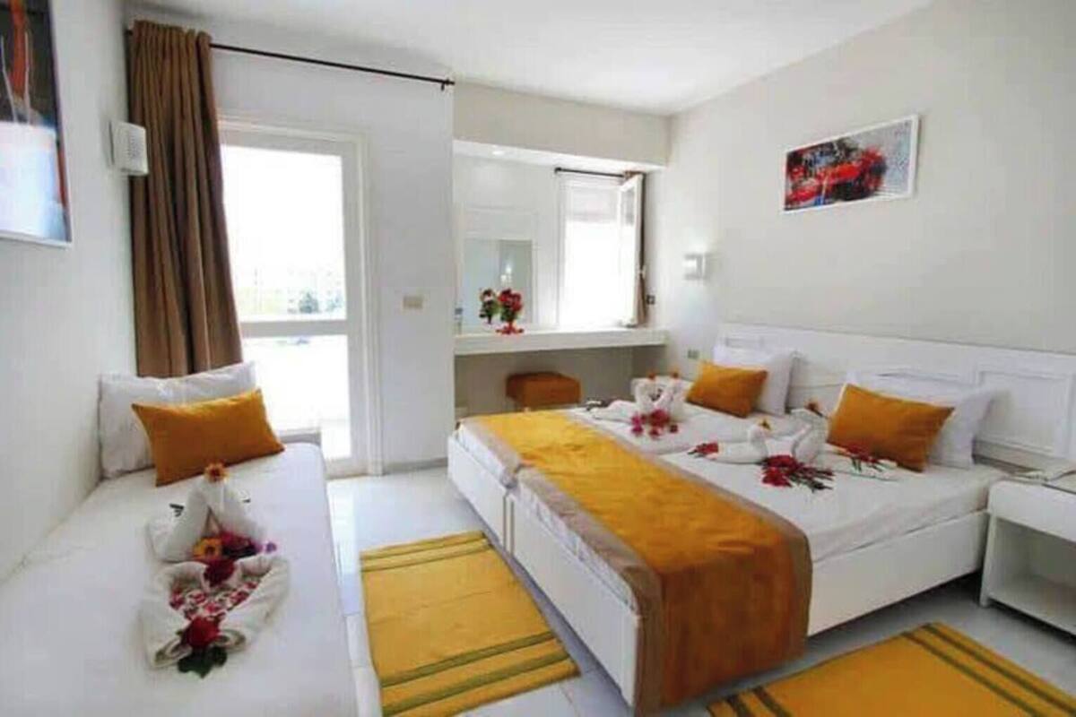Una habitación de hotel con dos camas, baño y ventana.