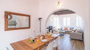 A dining area with a wooden table, white chairs, and a mirror with a decorative wreath. - La Bailonga Cómpeta by Ruralidays (Málaga)