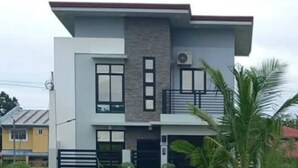 A modern two-story house with a flat roof, large windows, and a balcony. - Cozy Corner Transient House (Calapan City)