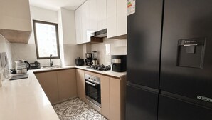 A modern kitchen with a black refrigerator, a stove, and a coffee maker. - Elegant Apartment Modern Design - 1006 (Lima)