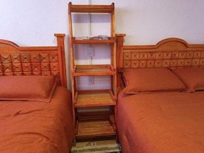 A bedroom with two beds, a wooden headboard, a built-in shelf unit, and a power outlet. - Rincon Hortensia apartments and loft - Apt de 1 habitacion 2 (Oaxaca de Juárez)