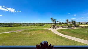 A golf course with a clear sky, palm trees, and a distant building. - Sunset Greens Retreat at Reunion-7603 (Kissimmee)