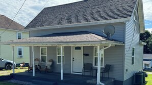 A two-story house with a covered porch, a satellite dish, and a garage door.