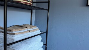 A bathroom with a towel rack holding folded towels and a decorative plant.
