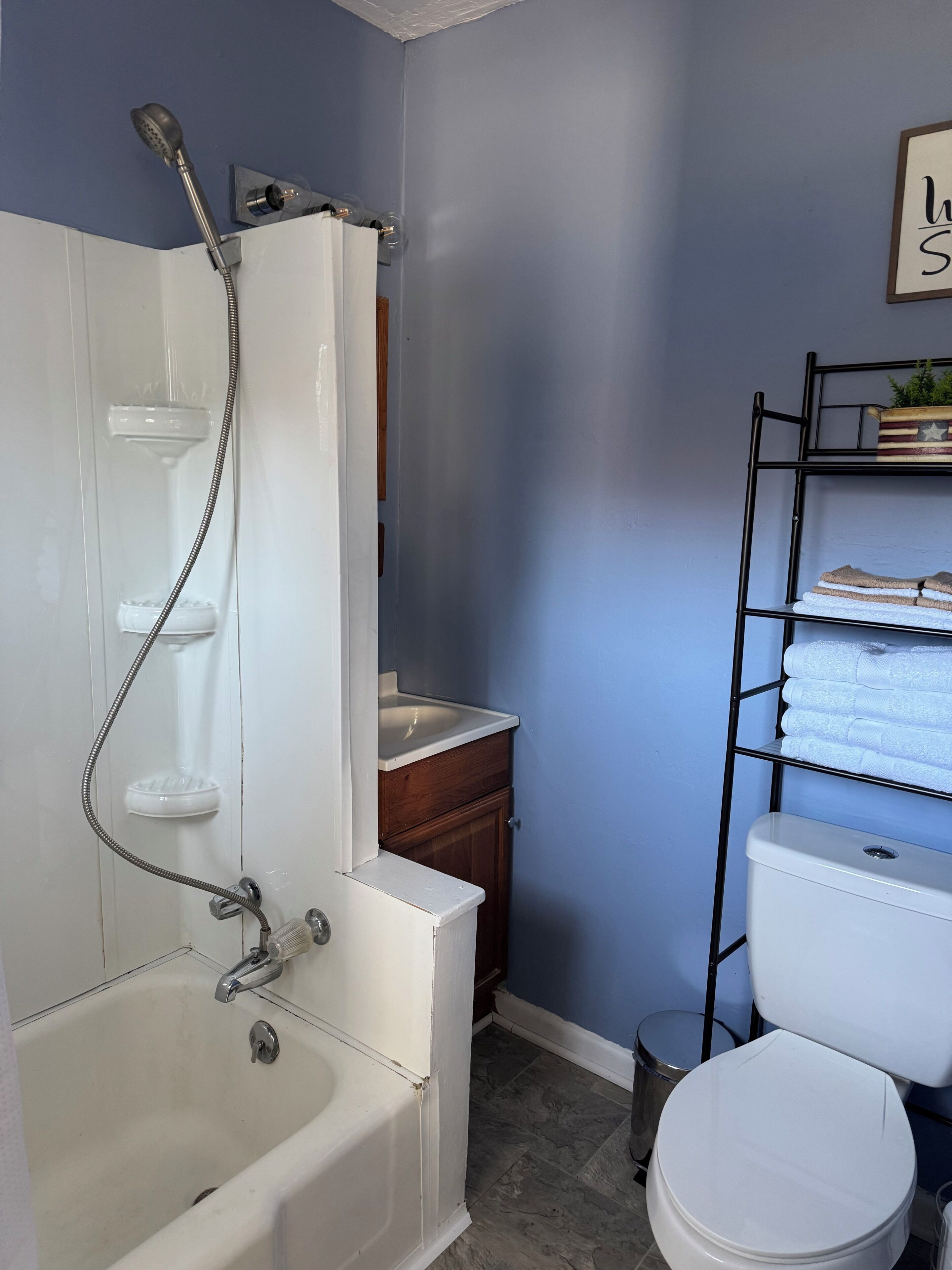 A bathroom with a bathtub, shower, sink, toilet, and a towel rack.
