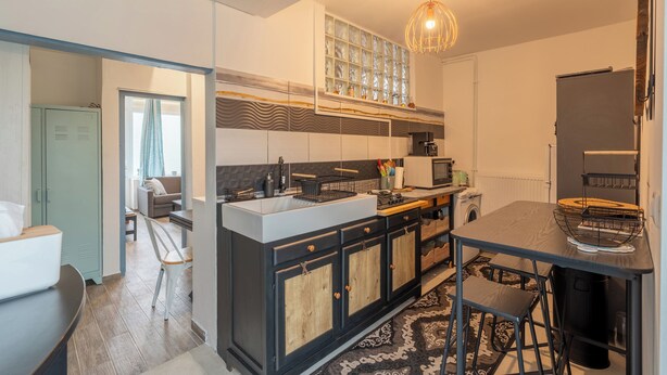 A modern kitchen with a central island, a dining table, and a built-in oven. - Le Sostranien - Jardin - Wifi (La Souterraine)