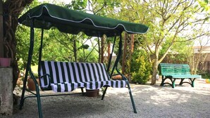 A green outdoor bench with a striped cushion, a covered swing, and a gravel path. - Le Sostranien - Jardin - Wifi (La Souterraine)