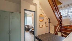 A room with a dining table, a sofa, a staircase, and a wardrobe. - Le Sostranien - Jardin - Wifi (La Souterraine)