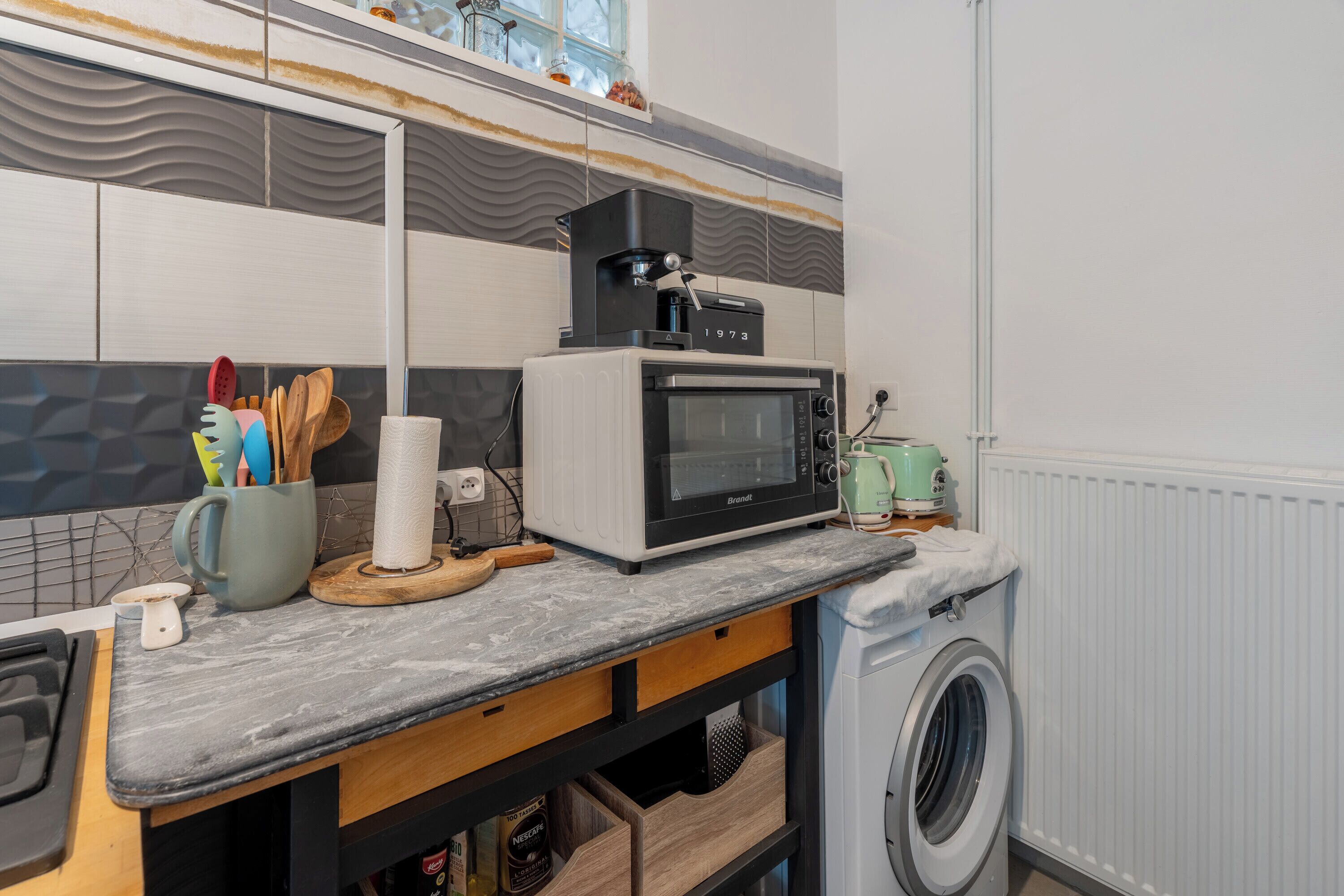 A kitchen with a microwave, coffee maker, and washing machine.