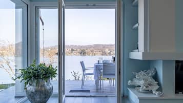 Ein Zimmer mit einem großen Fenster, einem Blumentopf, einem Tisch mit Stühlen und einem Kamin.