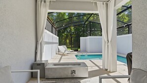 Ett takförsett utomhusområde med en pool, vita möbler och en modern design.