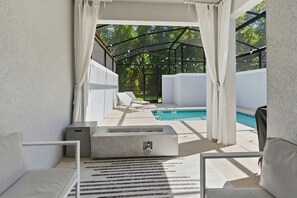 A covered outdoor area with a pool, white furniture, and a modern design. - Lovely Themed Villa w/ Private Pool | Storey Lake (2441) (Kissimmee)