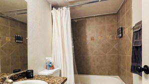 A bathroom with a sink, toilet, bathtub, and shower curtain. - The Hidden Gem of Dallas (Dallas)