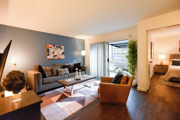 A modern living room with a sofa, armchair, coffee table, and artwork on the wall. - The Hidden Gem of Dallas (Dallas)