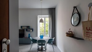 Un espace repas moderne avec une table ronde, des chaises, un vase et une fenêtre avec des rideaux.