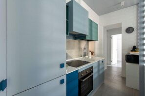 A modern kitchen with white and blue cabinetry, a black stove, and a microwave. - Azul Balcony near the Cala (PALERMO)