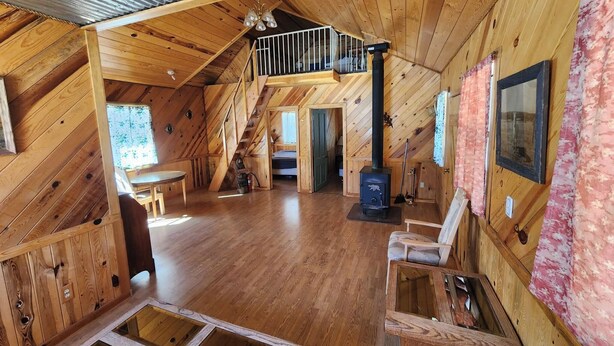 A wooden interior with a loft bedroom, a fireplace, and a dining area. - Beaver Creek Guest Ranch is your scenic getaway. (Blue)