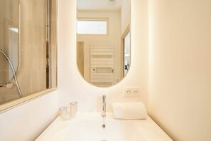 A bathroom with a white sink, a glass shower enclosure, a towel, and a mirror. - Spacious 2P Studio - Centre of Saint-tropez (Saint-Tropez)