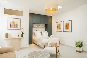 A modern hotel room with a bed, a seating area, a small table, and artwork on the walls. - Spacious 2P Studio - Centre of Saint-tropez (Saint-Tropez)