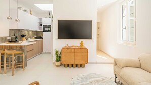 Ett modernt kök med en matplats, en träfärgad skänk och en stor, platt-TV som är monterad på väggen.