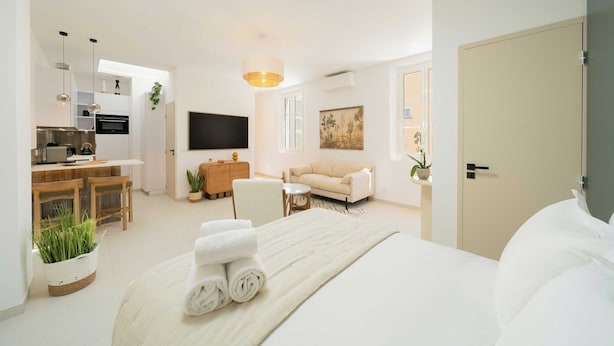 Ett modernt hotellrum med en säng, en soffa, en TV, en matplats och ett kök.