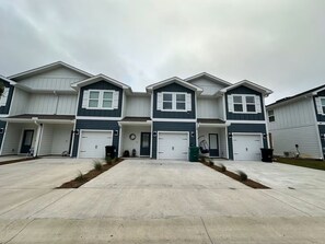 Eine Reihe von zweigeschossigen Reihenhäusern mit Vorgarten, Garage und Betonauffahrt.