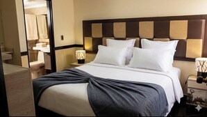 Ein Hotelzimmer mit Bett, Nachttischen, einer Lampe und Blick ins Bad.