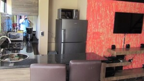 Eine moderne Küche mit Kühlschrank, Mikrowelle und einem flachbildschirmigen Fernseher an der Wand.