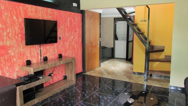 Eine Hotelhalle mit einem Flachbildfernseher, einem hölzernen Empfangsbereich und einer Treppe, die zu einer oberen Etage führt.