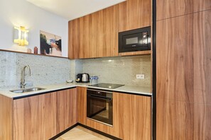 Eine moderne Küche mit Holzschränken, einer Edelstahl-Spüle, einer eingebauten Mikrowelle und einem Geschirrspüler.