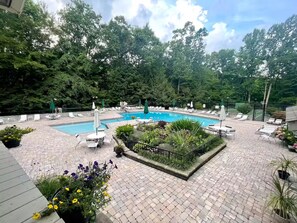 A swimming pool surrounded by lounge chairs and umbrellas, with a garden area in the center. - Fox Hollow Hideaway - Cabin (Gatlinburg)