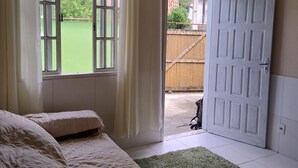 A bedroom with a bed, a window with curtains, a door, and a green carpet.