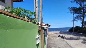 A coastal road with a green wall, a wooden fence, and a clear view of the sea.